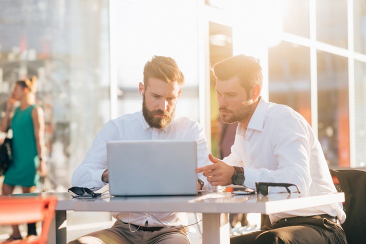 Two men discuss at laptop